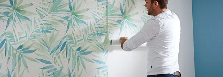 Person bringt Tapete mit Muster an